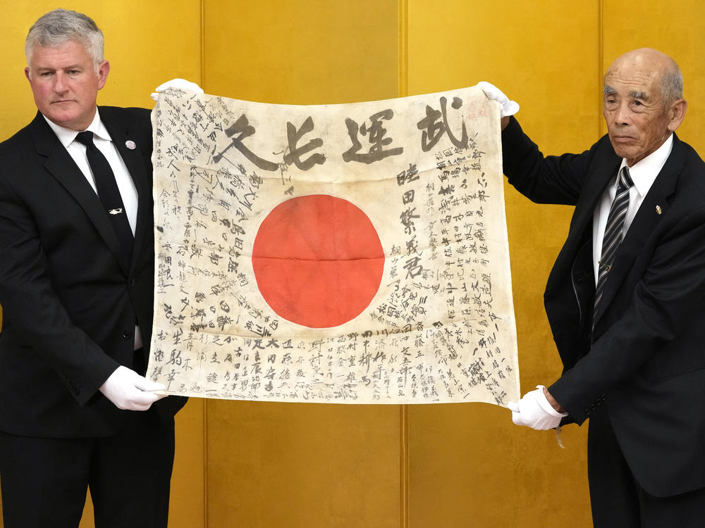 USS Lexington Museum executive director Steve Banta (left) and Toshihiro Mutsuda, the son of Japanese soldier Shigeyoshi Mutsuda, hold together the late soldier's 