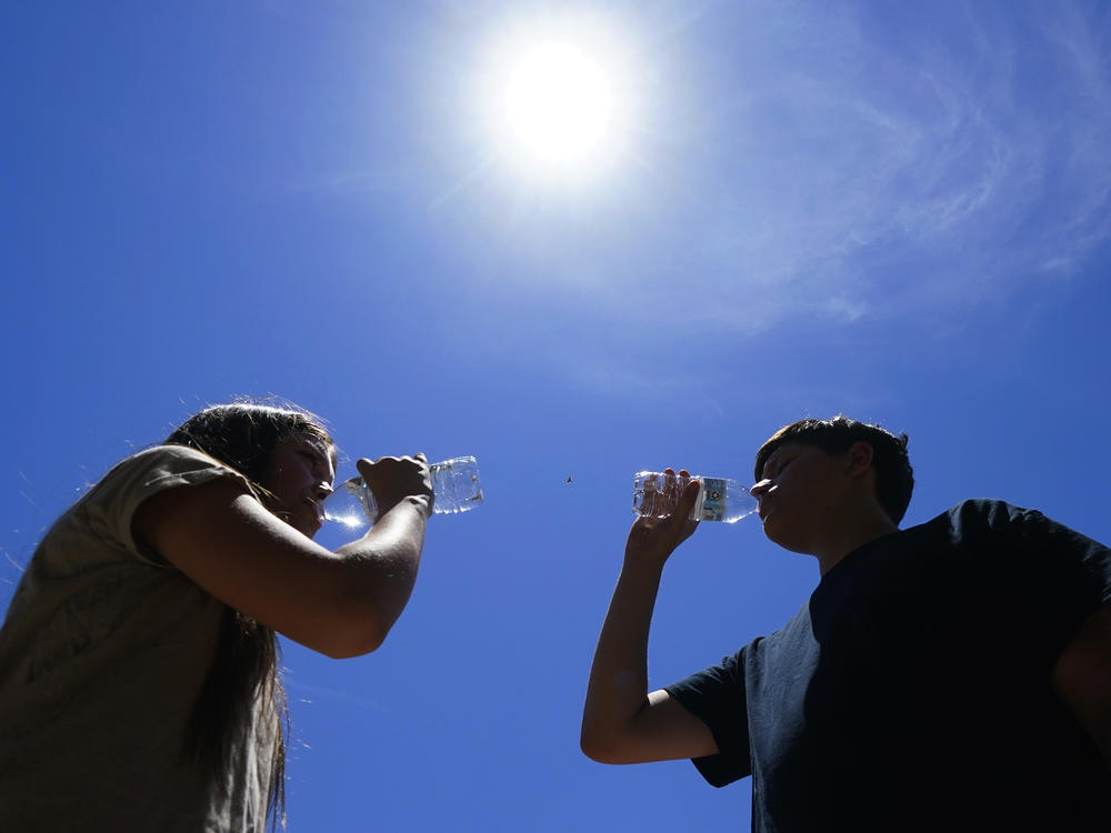 Tony Berastegui Jr., right, and his sister Giselle Berastegui drink water, Monday, July 17, 2023, in Phoenix. A historic heat wave that turned the Southwest into a blast furnace throughout July is beginning to abate with the late arrival of the monsoon rains.