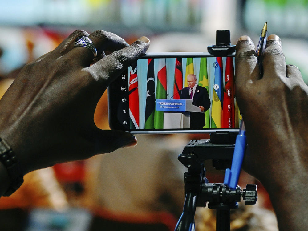 Russian President Vladimir Putin is seen on a phone screen as he attends a joint statement with President of Comoros Azali Assoumani at the Russia Africa Summit in St. Petersburg, Russia, Friday, July 28, 2023.