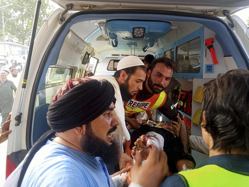 In this photo provided by Rescue 1122 Head Quarters, rescue workers carry a wounded man after a bomb explosion in the Bajur district of Khyber Pakhtunkhwa, Pakistan on Sunday.