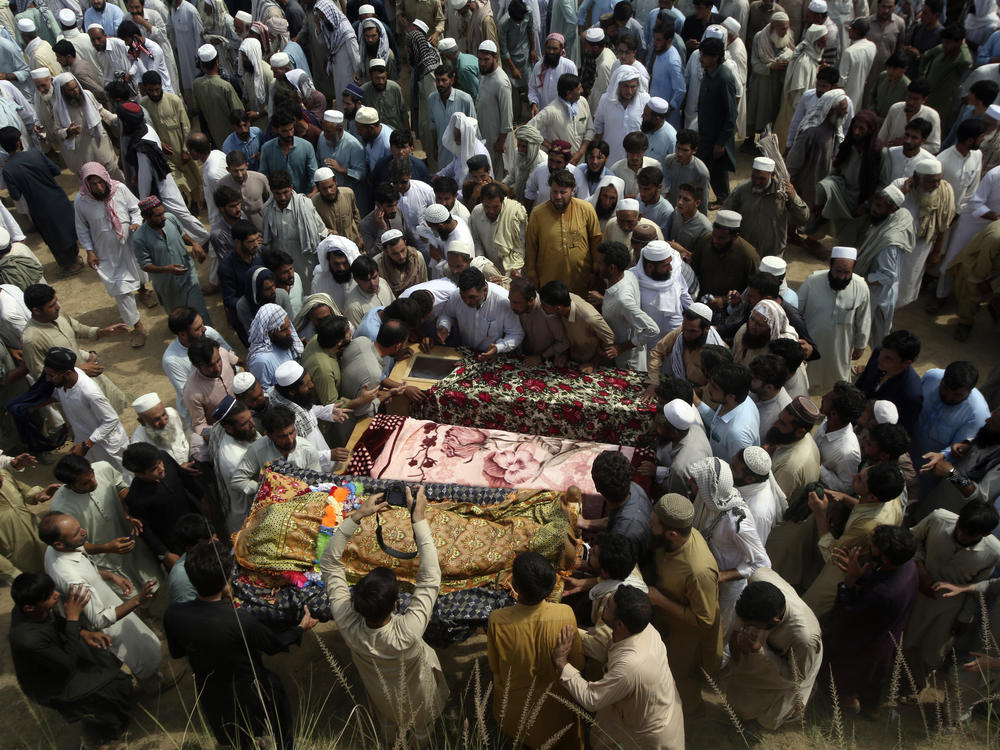 Relatives and mourners gather around the caskets of victims who were killed in Sunday's suicide bomber attack in the Bajur district of Khyber Pakhtunkhwa, Pakistan, Monday, July 31, 2023.