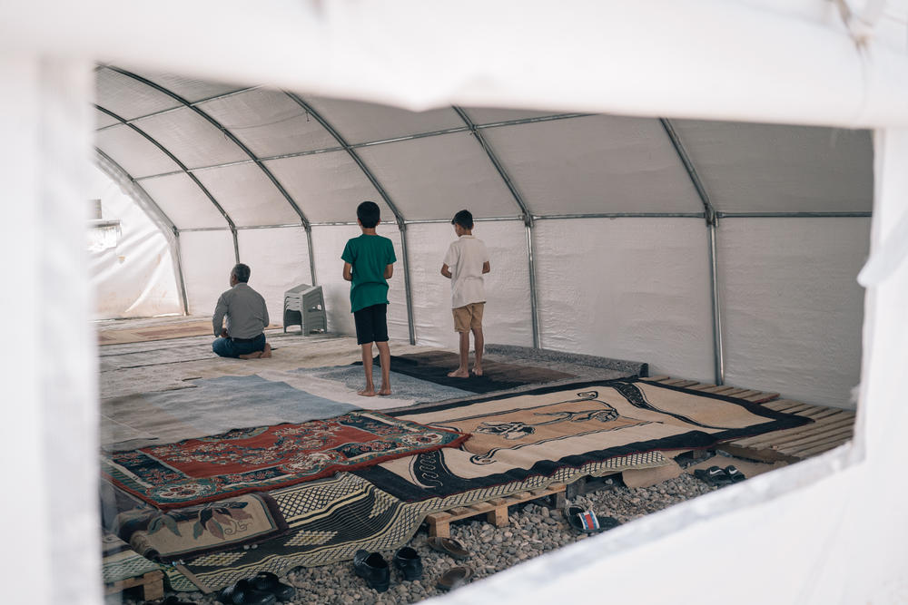 A man and two boys pray in a makeshift mosque set up in a tent in Adiyaman.