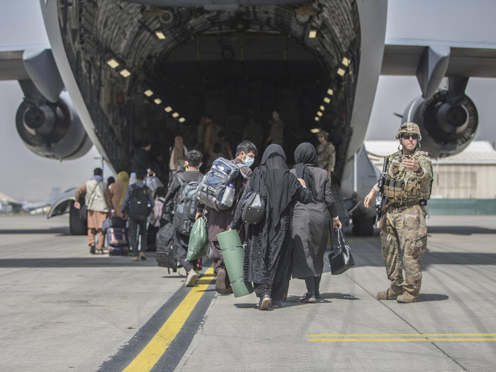 Families begin to board a U.S. Air Force Boeing C-17 Globemaster III during an evacuation at Hamid Karzai International Airport in Kabul in August 2021.