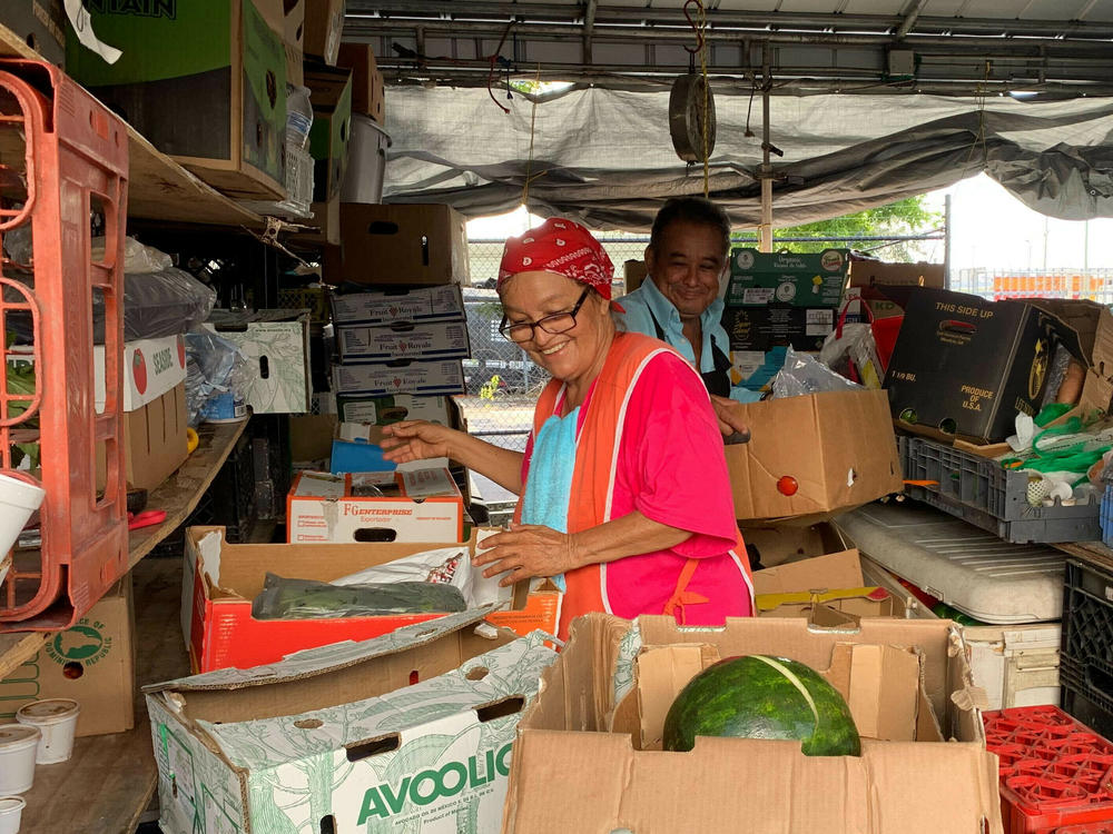 Bessy Hernandez works with her ex-husband Nelson Cerna at their Tropicana Flea Market produce stand. Although the two divorced years ago, they continue to work together.