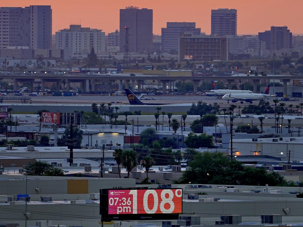 A sign displays an an unofficial temperature as jets taxi at Sky Harbor International Airport at dusk, July 12 in Phoenix.