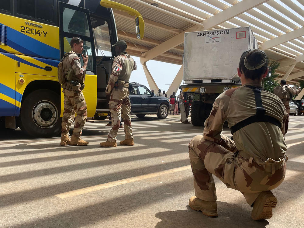 French soldiers assist mostly French nationals in a bus waiting to be airlifted back to France on a French military aircraft, at the international Airport in Niamey, Niger, Tuesday, Aug. 1, 2023.
