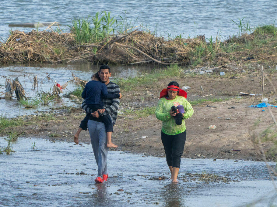 Migrants walk in the water along the Rio Grande border with Mexico in Eagle Pass, Texas.