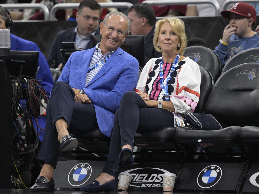 Dick DeVos (left) and former Secretary of Education Betsy DeVos watch from courtside seats during a game between the Orlando Magic and the Brooklyn Nets on March 26 in Orlando, Fla. The Magic is owned by the DeVos family.