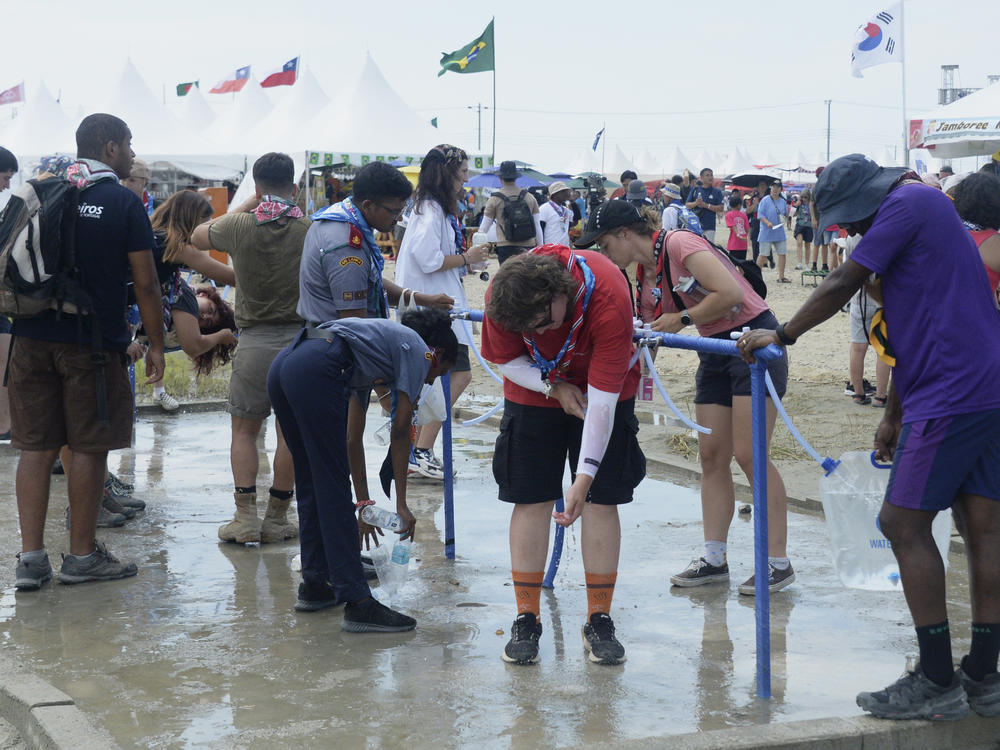 Attendees of the World Scout Jamboree cool off with water at a scout camping site in Buan, South Korea, on Friday.