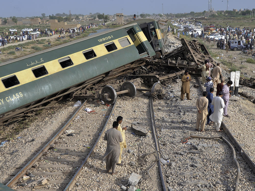 Local residents examine damaged cars of a passenger train which was derailed near Nawabshah, Pakistan. Railway officials say some passengers were killed and dozens more injured when a train derailed near the town of Nawabshah.