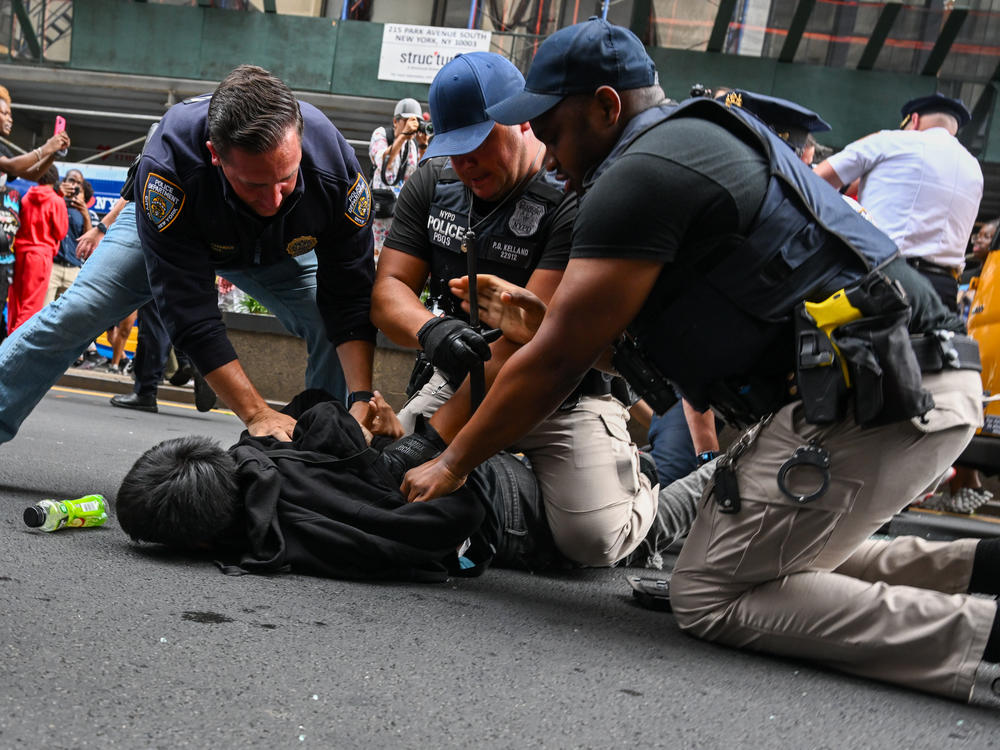 Members of the NYPD arrest people after responding to thousands of people gathered for a 