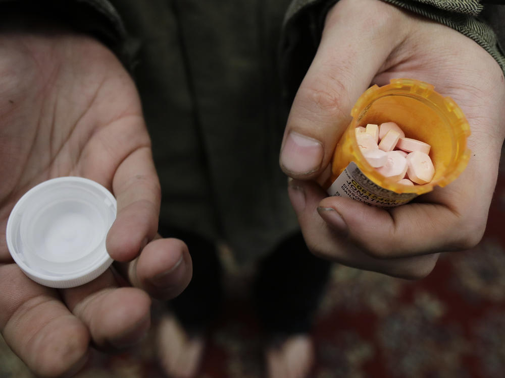 A person with addiction holds a bottle of buprenorphine, a medicine that prevents withdrawal sickness in people trying to stop using opiates, as he prepares to take a dose in a clinic in Olympia, Wash (AP Photo/Ted S. Warren)