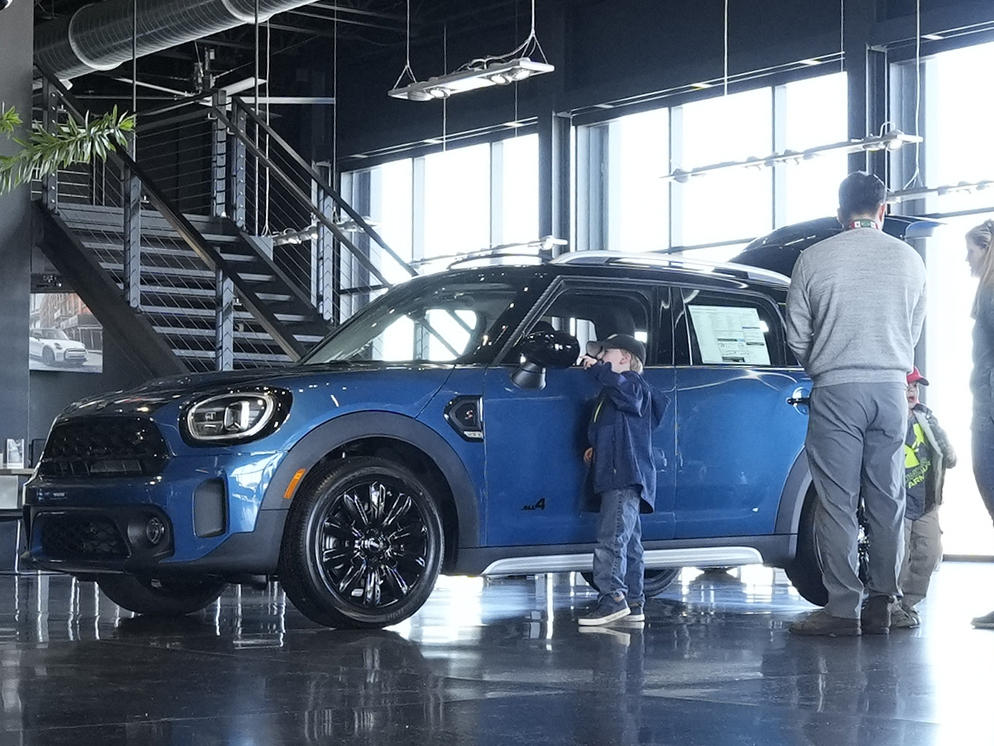 Potential buyers look at a 2023 Cooper Countryman S sports-utility vehicle on the floor of a Mini dealership on Friday, Feb. 17, 2023, in Highlands Ranch, Colo.