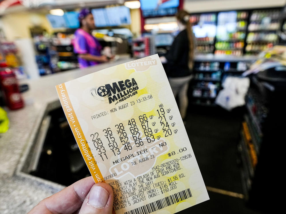 A Mega Millions ticket is seen as a person makes a purchase inside a convenience store, ahead of Tuesday's Mega Millions drawing of $1.55 billion, Monday, Aug. 7, 2023, in Kennesaw, Georgia.