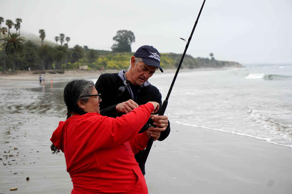 Marine biologist Steve Palumbi helps Chumash cultural educator Mia Lopez with her fishing rod on a scientific sampling trip.