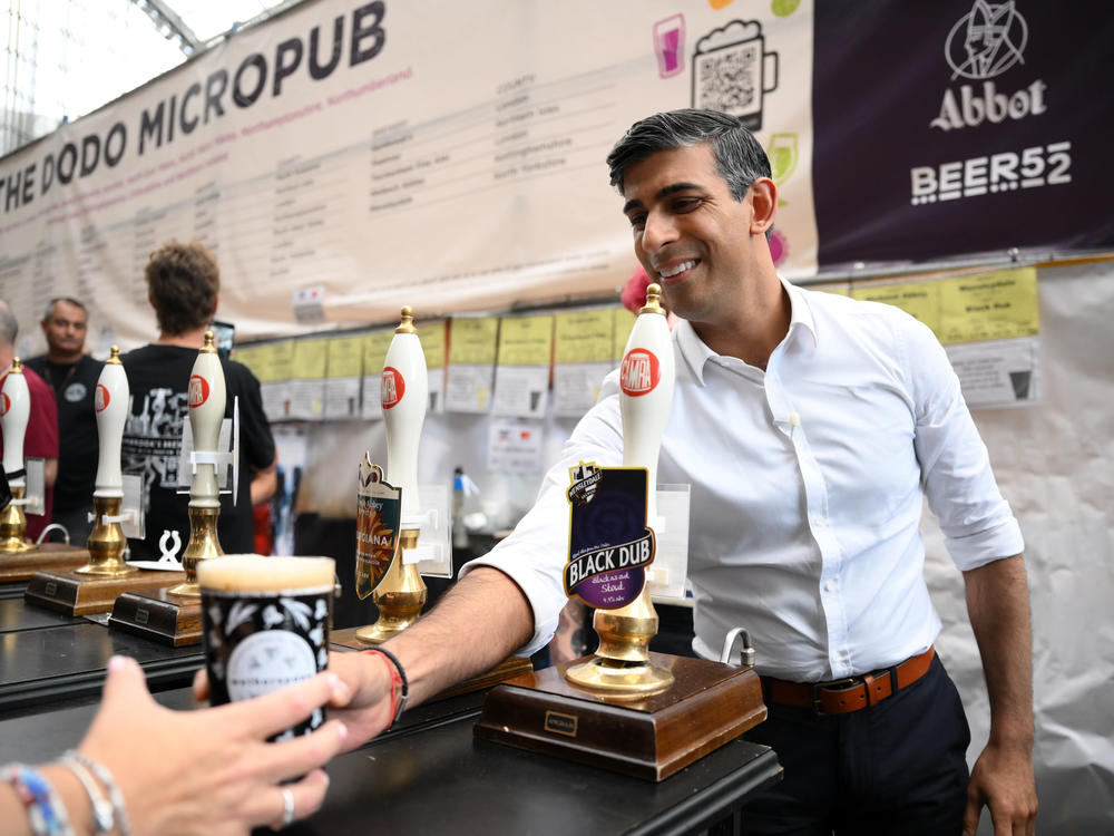 Britain's Prime Minister Rishi Sunak serves a pint of stout that he poured during a visit to the Great British Beer Festival on Aug. 1, in London. He was heckled by a pub owner who was unhappy about the rise in duty for beverages with higher alcohol content.