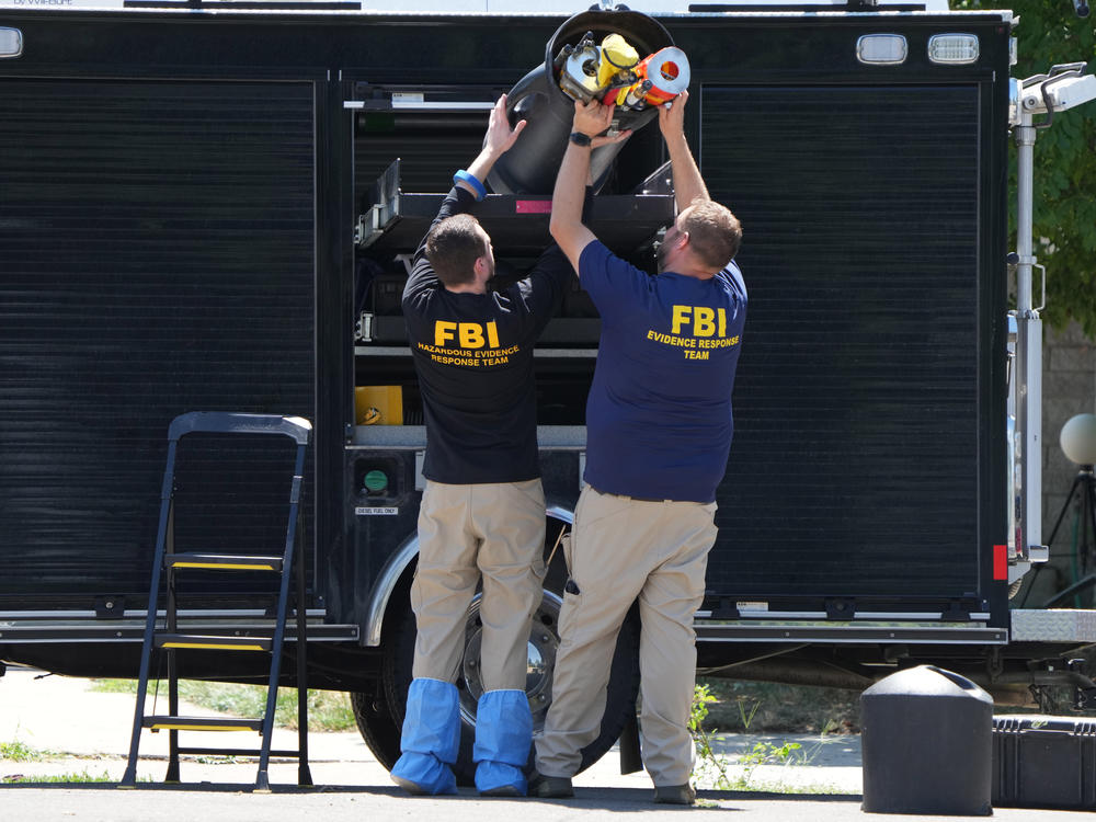 FBI officials unload the equipment as they process the home of Craig Robertson who was shot and killed by the FBI in a raid on his home this morning on August 9 in Provo, Utah.