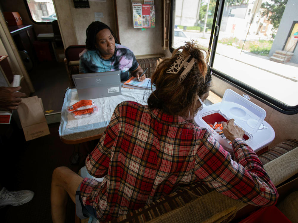 LaShonda Jefferson (left), a community health educator, talks with a woman who drops off used needles into a bin on the van.