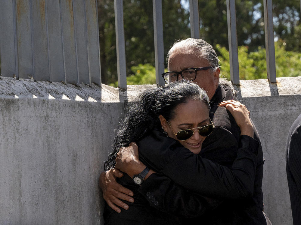 Lorena Villavicencio, sister of slain presidential candidate Fernando Villavicencio, embraces her husband outside the morgue where her brother's body is being held, in Quito, Ecuador, Thursday, Aug. 10, 2023.
