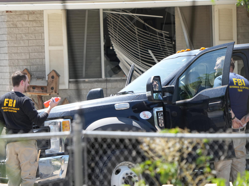 FBI agents process the home of Craig Robertson who was shot and killed by the FBI in a raid on his home on Wednesday in Provo, Utah. The FBI was investigating alleged threats by Robertson to President Biden ahead of the president's visit to the state this week.