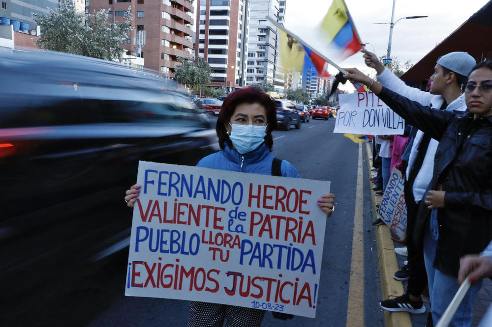 Following Villavicencio's assassination, a woman holds a sign reading: 