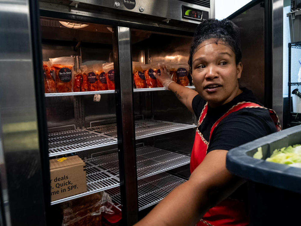 Cunningham sorts through packaged kimchi in the fridge.