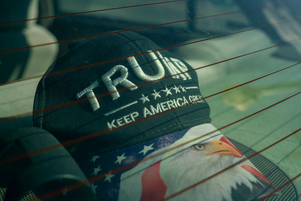 A Trump hat is visible through the window of a car next to a cigar shop in downtown Martinsburg, West Virginia.
