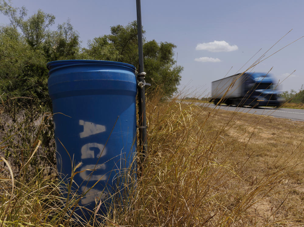 A water station for immigrants containing sealed jugs of fresh water sits along a fence line near a roadway in rural Jim Hogg County, Texas, on July 25.