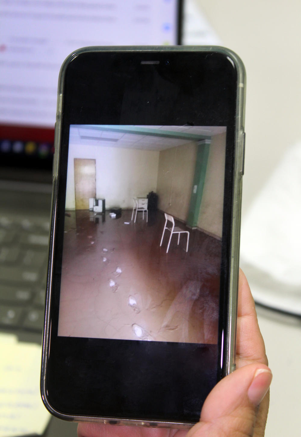 A staff member holds up a photo of a school-based mental health center in Comerio, in central Puerto Rico, after Hurricane Fiona hit. The center, run by the nonprofit Instituto Nueva Escuela, had a waterline that was over 6 feet high, half covering some posters on the walls. When staff members could finally enter the building, they saw dead fish and pools of dirty water.