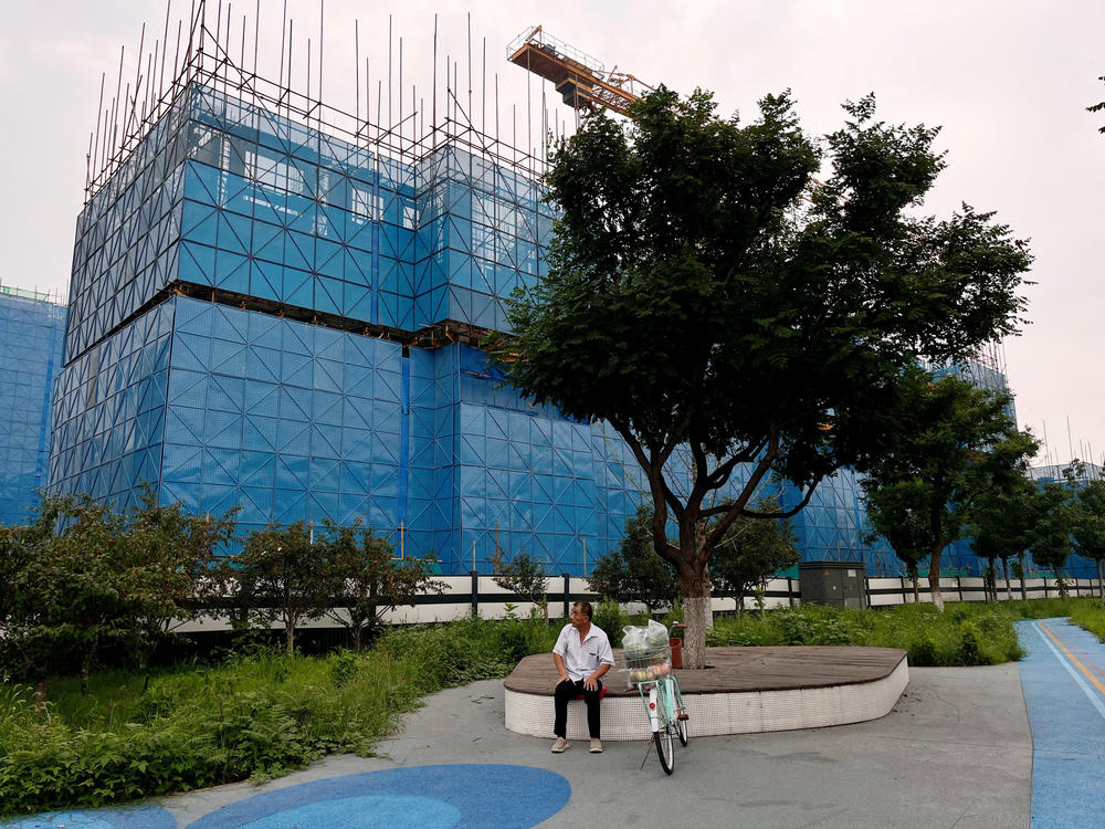 A person sits near a construction site of residential buildings by Chinese developer Country Garden, in Beijing, Aug. 11. Country Garden is facing major financial challenges.