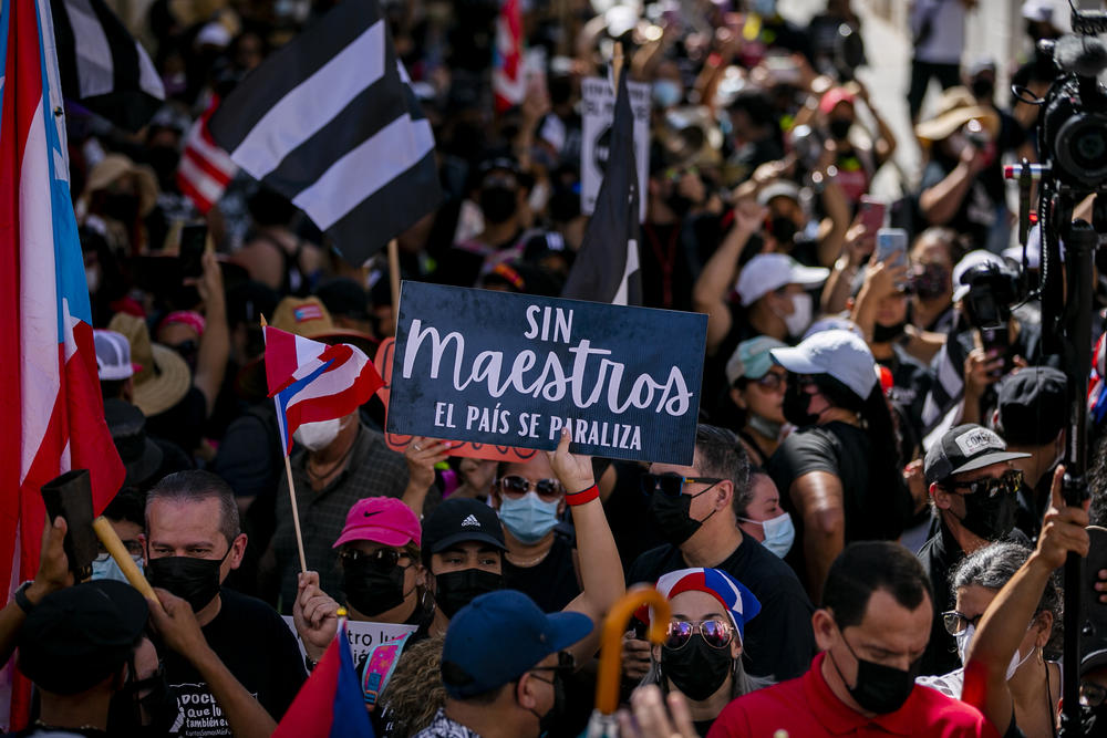 A demonstrator holds a sign that reads, in Spanish, 