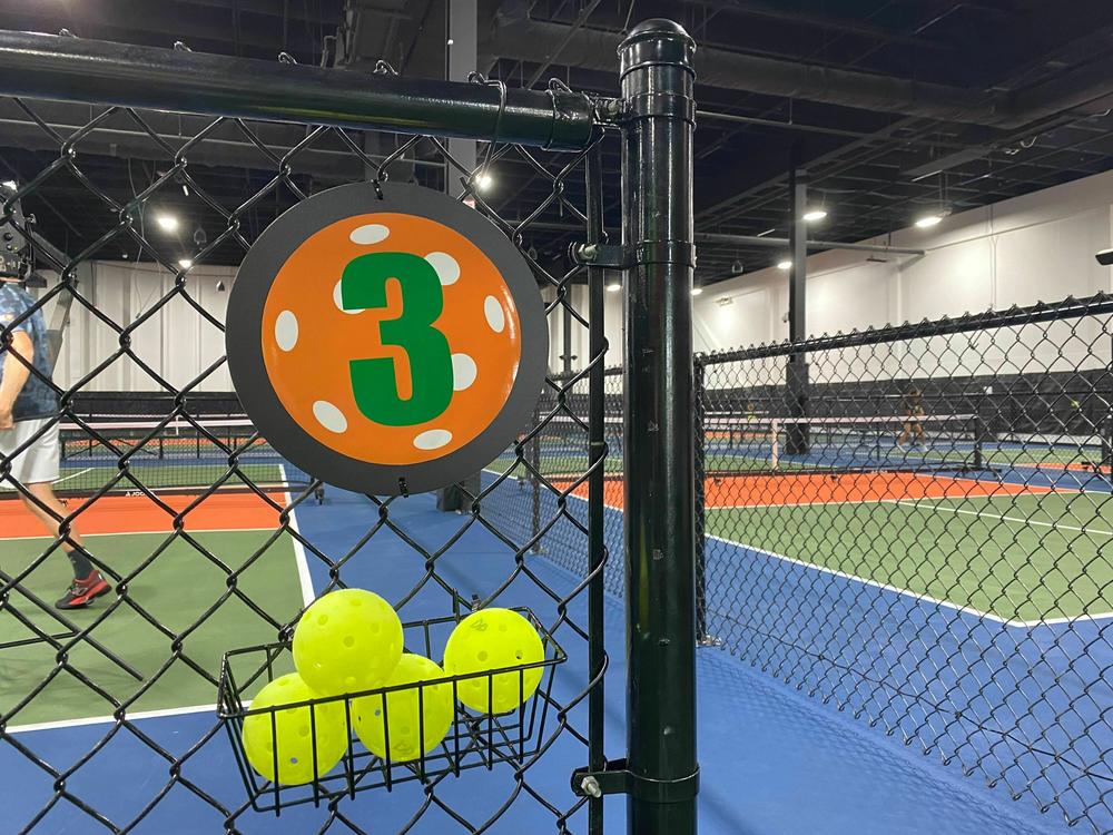 Pickleballs hang on a fence at the North Bethesda location of Dill Dinkers on August 7, 2023. The location is one of three open Dill Dinkers.