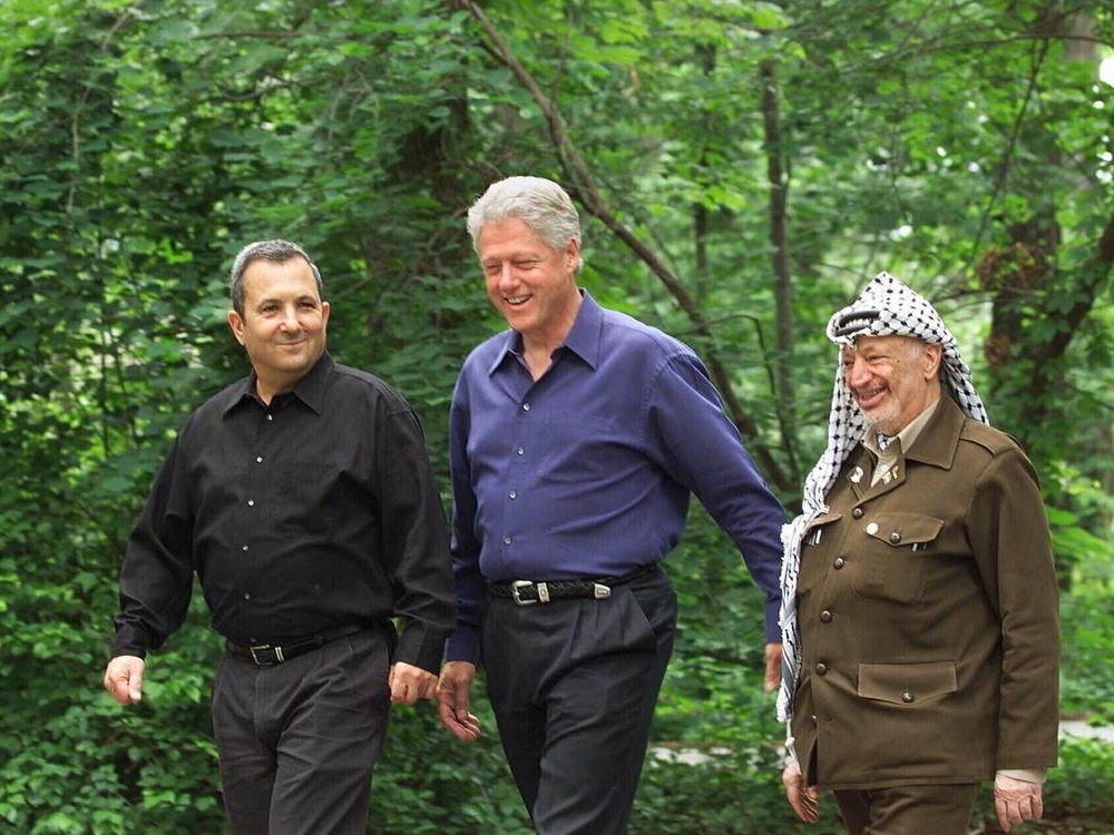 President Bill Clinton, Israeli Prime Minister Ehud Barak, left, and Palestinian leader Yasser Arafat walk on the grounds of Camp David at the start of the Mideast summit on July 11, 2000.