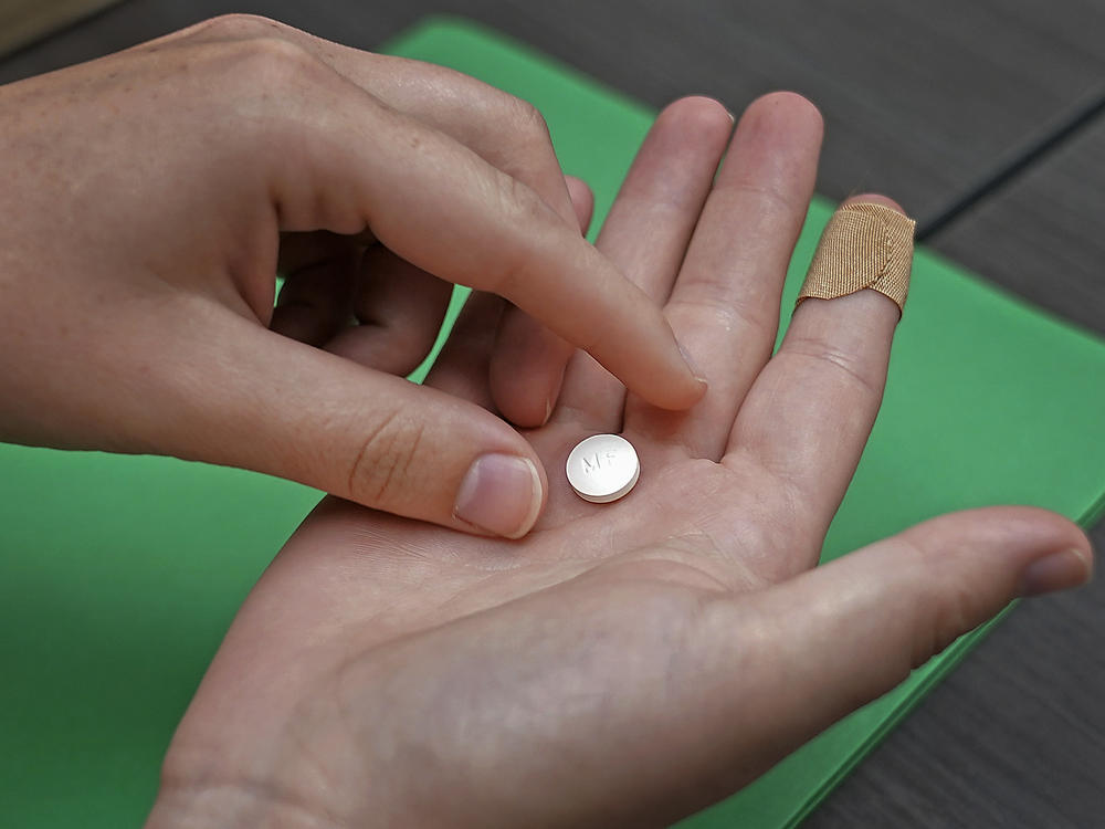 A patient prepares to take mifepristone, for a medication abortion. A federal appeals court ruled to impose new restrictions on the drug Wednesday but the ruling will not take effect until the Supreme Court weighs in.