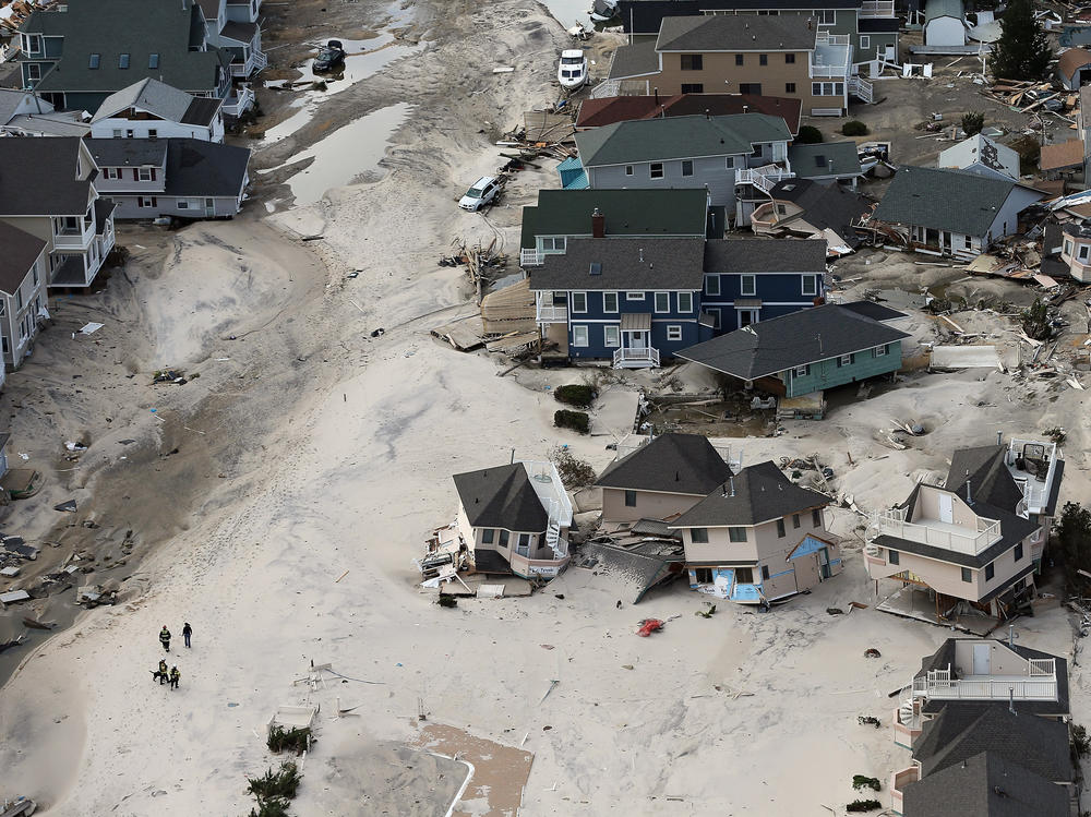 Rescue workers in Seaside Heights, New Jersey, walk past homes wrecked by Superstorm Sandy in 2012. Early reports suggested dozens of people died in the storm, but later assessments found the death toll to be at least 20 times higher.