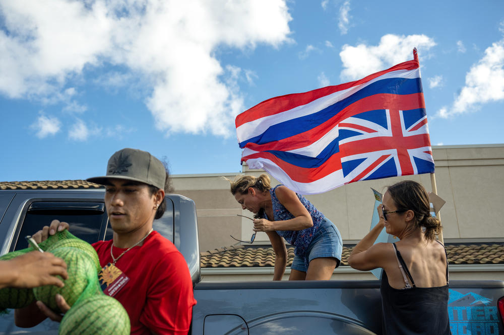 At last, Jaylen Kaneaku lost his home in the wildfires and is helping transport donated items to this distribution center which has been set up by the indigenous community in Lahaina. Helping unload in the truck is Mandy Grace and Erica Goldsmith, right. Jayden hung the Hawaiian flag upside down on his truck as a sign that the state is in distress.