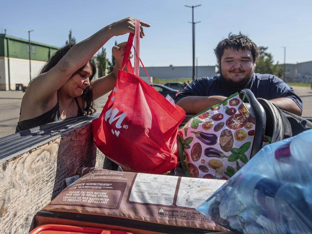 Hay River, N.W.T. fire evacuees Tanisha Edison and her boyfriend Mason Bruneau go through their belongings at the evacuee center in St. Albert, Alberta, on Wednesday, Aug. 16, 2023.