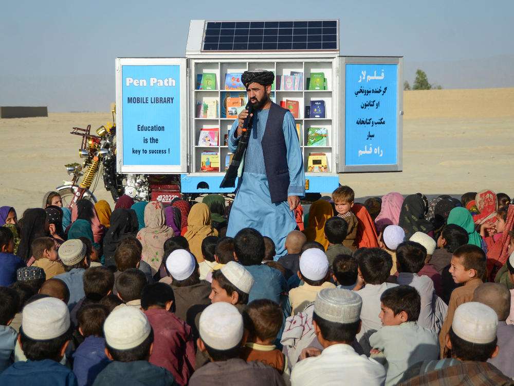 Matiullah Wesa, cofounder of the education charity PenPath in Afghanistan, speaks to children during a class next to his mobile library in a district of Kandahar Province. Wesa and his brother were among the Afghan men who have called for the Taliban to reverse its bans on higher education for girls. He was arrested in March and has been held in prison since then with no formal charges.