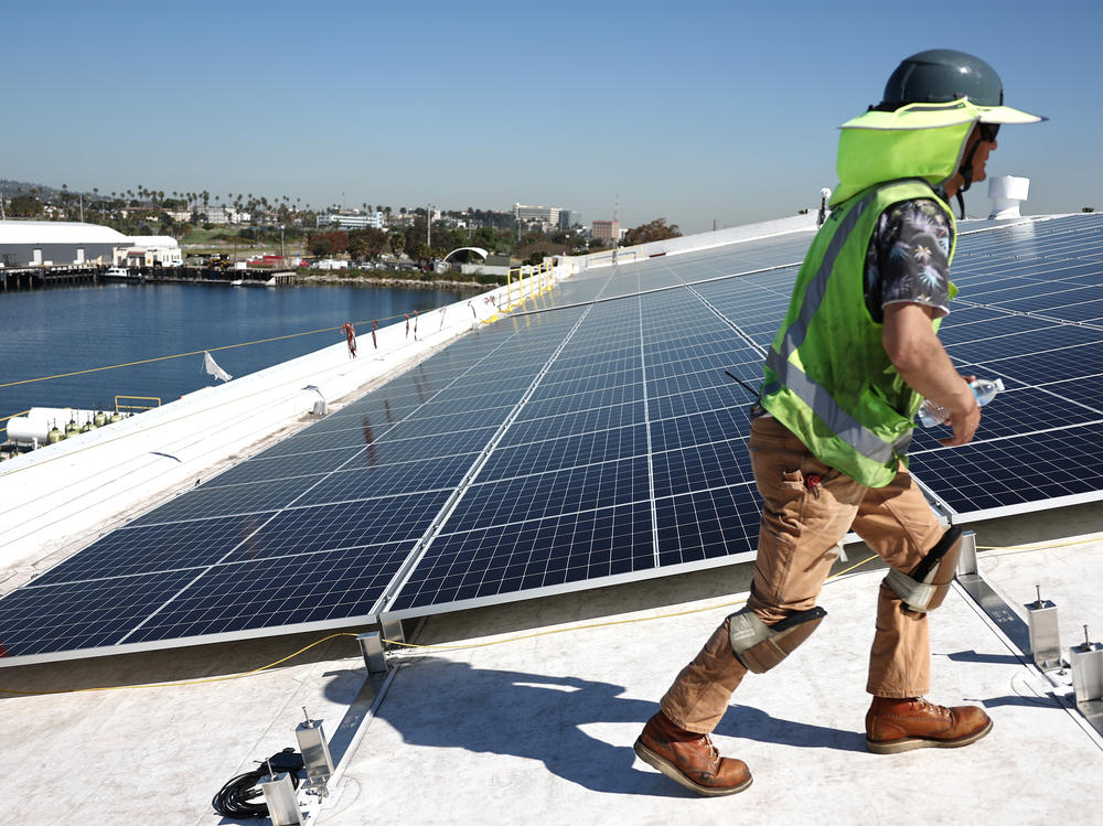 Workers install solar panels on a rooftop at AltaSea's research and development facility at the Port of Los Angeles on April 21, 2023.
