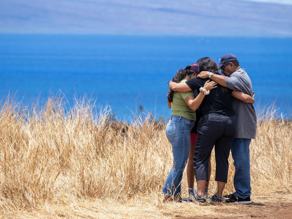 Volunteers helping those who lost homes in Lahaina stop to pray on a hillside. The town is surrounded by dry, invasive grasses which are highly flammable.