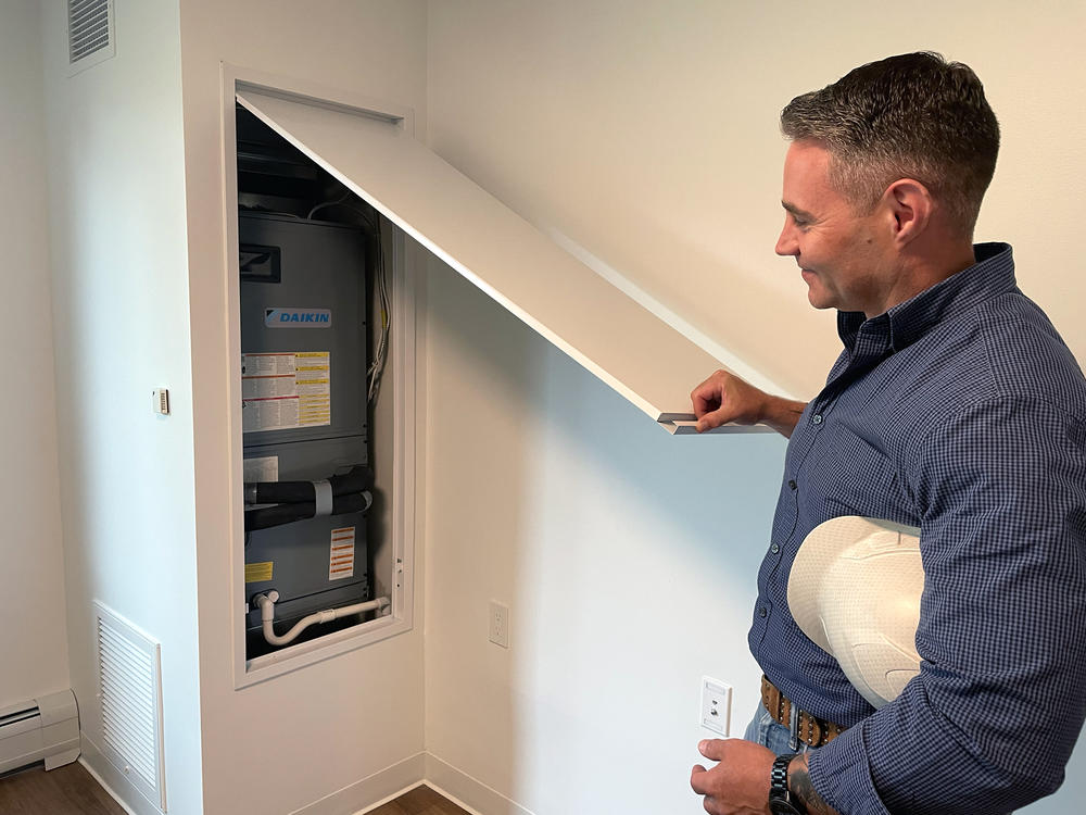 2Life Communities facilities director Joe O'Toole lifts a panel to reveal a portion of the variable refrigerant flow system he's installed in a Newton, Mass., apartment building. It provides heating or cooling throughout the year based on demand, along with air filtration.