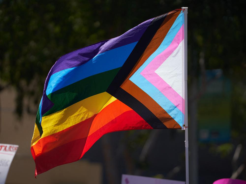 A business owner was fatally shot Friday after someone allegedly took issue with a Pride flag she had displayed at her clothing store in Cedar Glen, Calif. Here, a Progress Pride Flag is held above a crowd of LGBTQ+ activists in West Hollywood, Calif., in April 2023.
