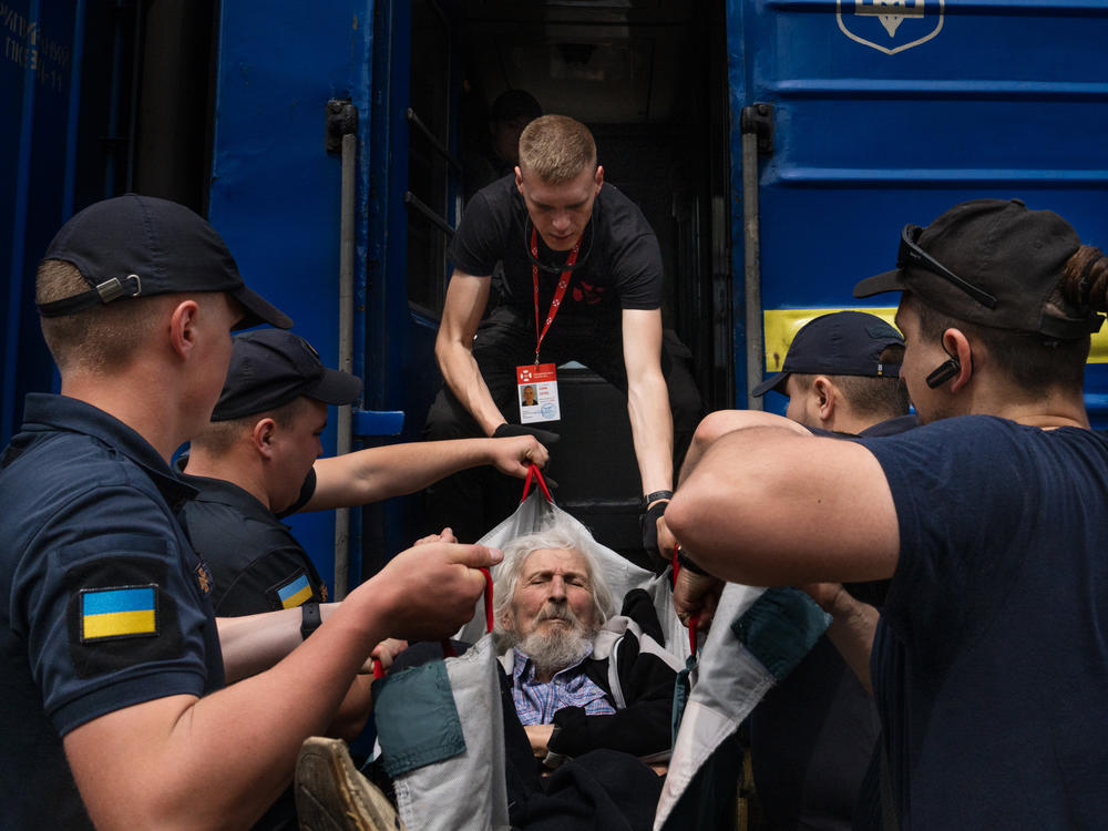 Eduard Skoryk (center) helps lift Viktor Nesterov onto an evacuation train.