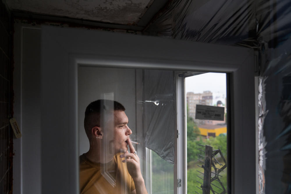 Skoryk smokes a cigarette looking out the window of his apartment.