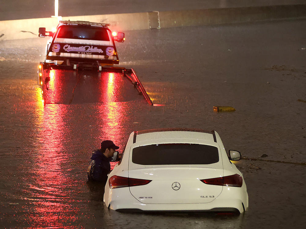 A tow truck driver attempts to pull a stranded car out of floodwaters on the Golden State Freeway as tropical storm Hilary moves through the area on August 20, 2023 in Sun Valley, California.
