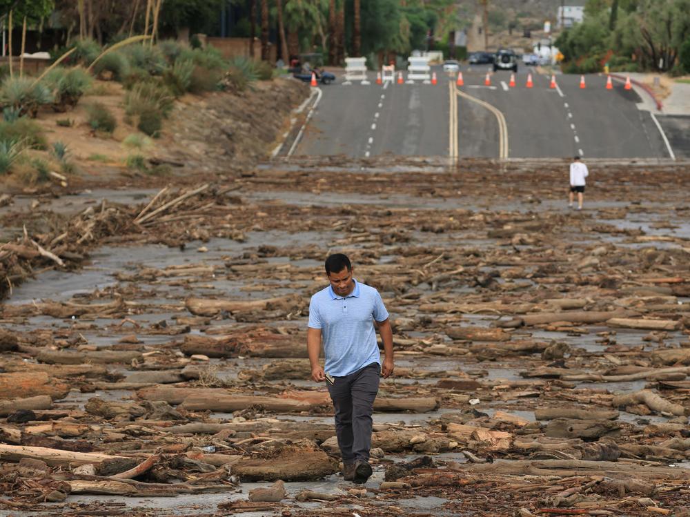A worker from the Coachella Valley Water Department surveys debris flowing across a road following heavy rains from Tropical Storm Hilary, in Rancho Mirage, Calif., on Monday.