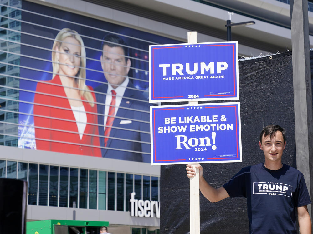 A former President Donald Trump supporter stands near the Fiserv Forum Tuesday as setup continues for Wednesday's Republican presidential debate in Milwaukee.