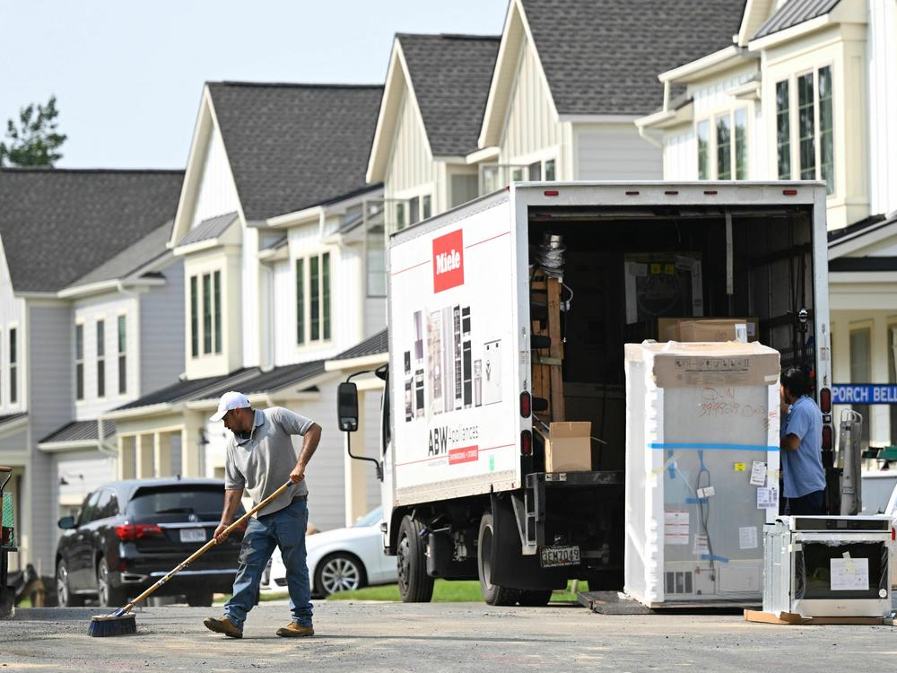 A maintenance worker sweeps the street in front of a row of new homes in Fairfax, Va., on Aug. 22. Sales of new homes are taking off as current homeowners are reluctant to sell their houses, because they would face a higher mortgage for their next one.