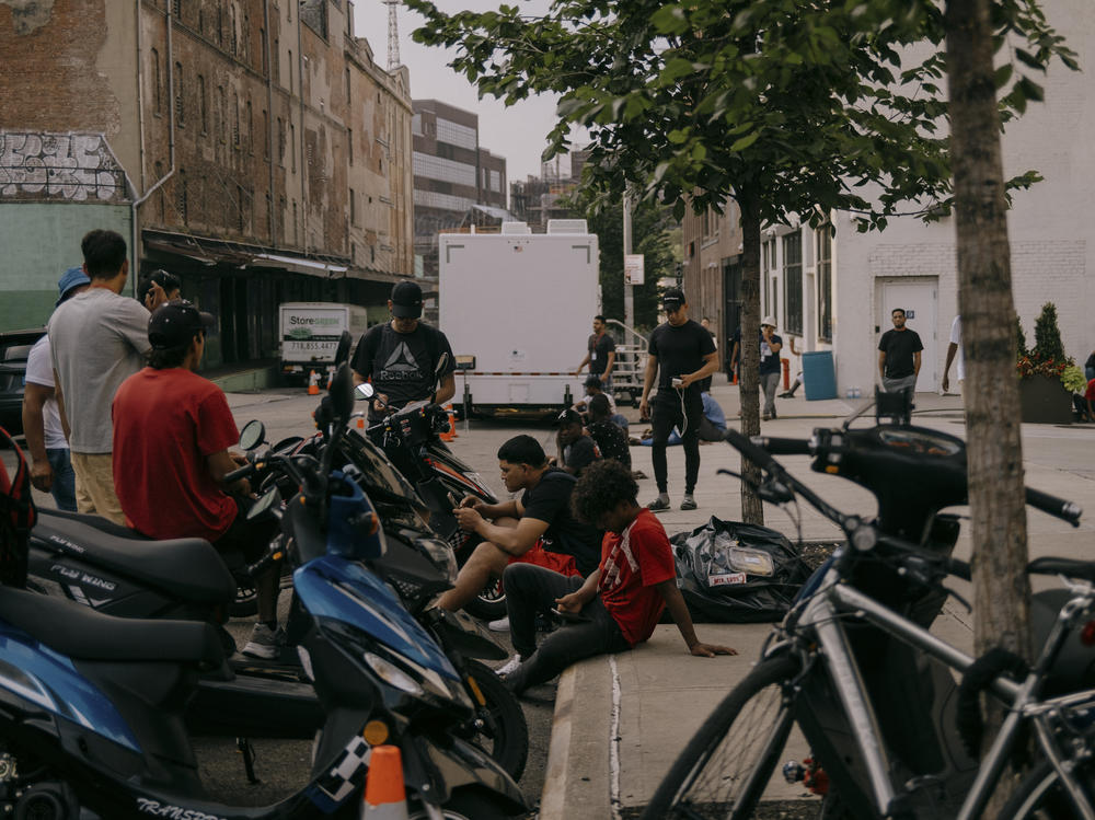 Migrants at the Clinton Hill Shelter seek relief from the overcrowded confinements of 47 Hall St. Residents working as delivery drivers wait for orders to come in on July 19 in Brooklyn, N.Y.