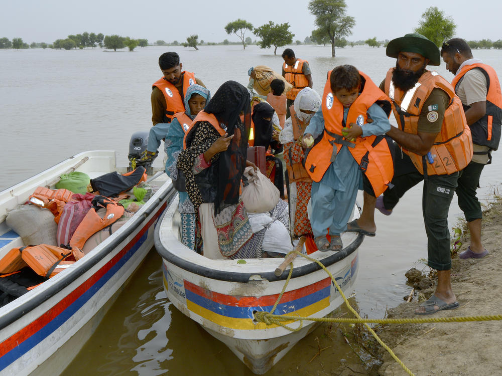 Rescue workers evacuate villagers through a boat from a flooded area of Pakpattan district of Pakistan's Punjab province, Wednesday, Aug. 23, 2023.